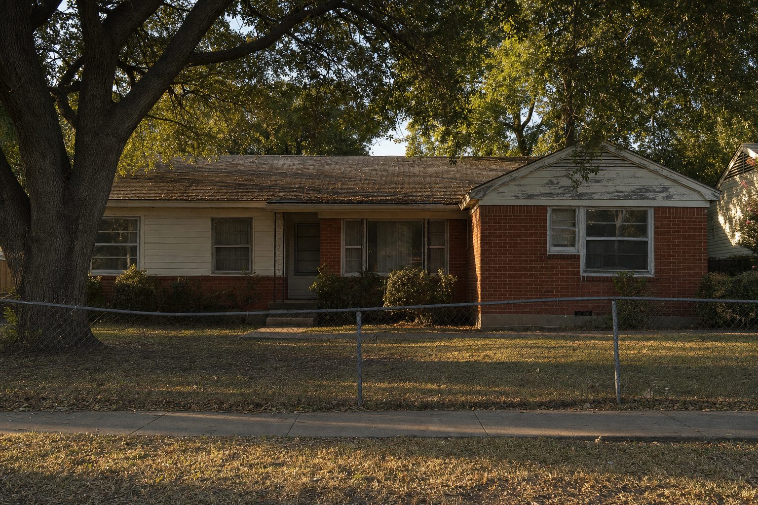 A modest 1960s brick and siding ranch house in Pleasant Grove, Dallas — an inherited property with mature oak and deferred maintenance