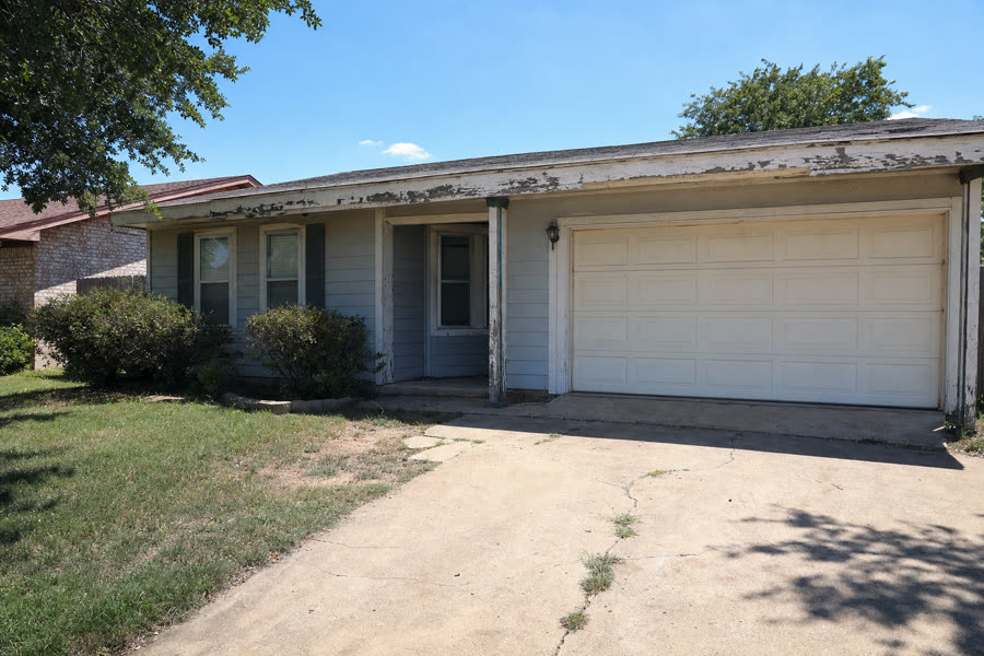 Sun-faded DFW ranch home with peeling paint and weathered trim