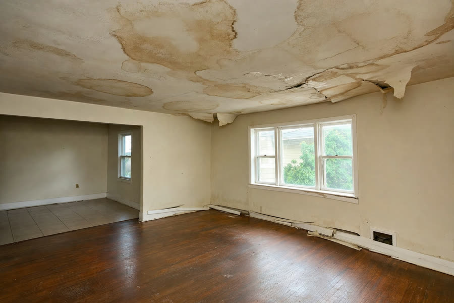 Living room ceiling with water stains and warped drywall