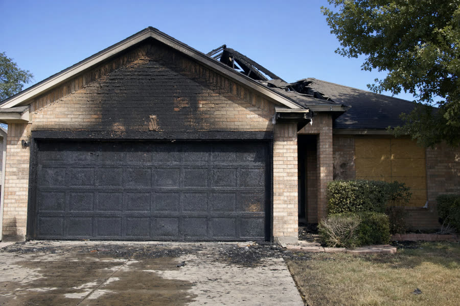 Exterior of a Texas home with charred garage door and burned roof