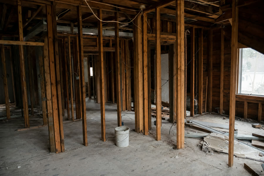 Stripped interior with exposed studs and abandoned renovation debris